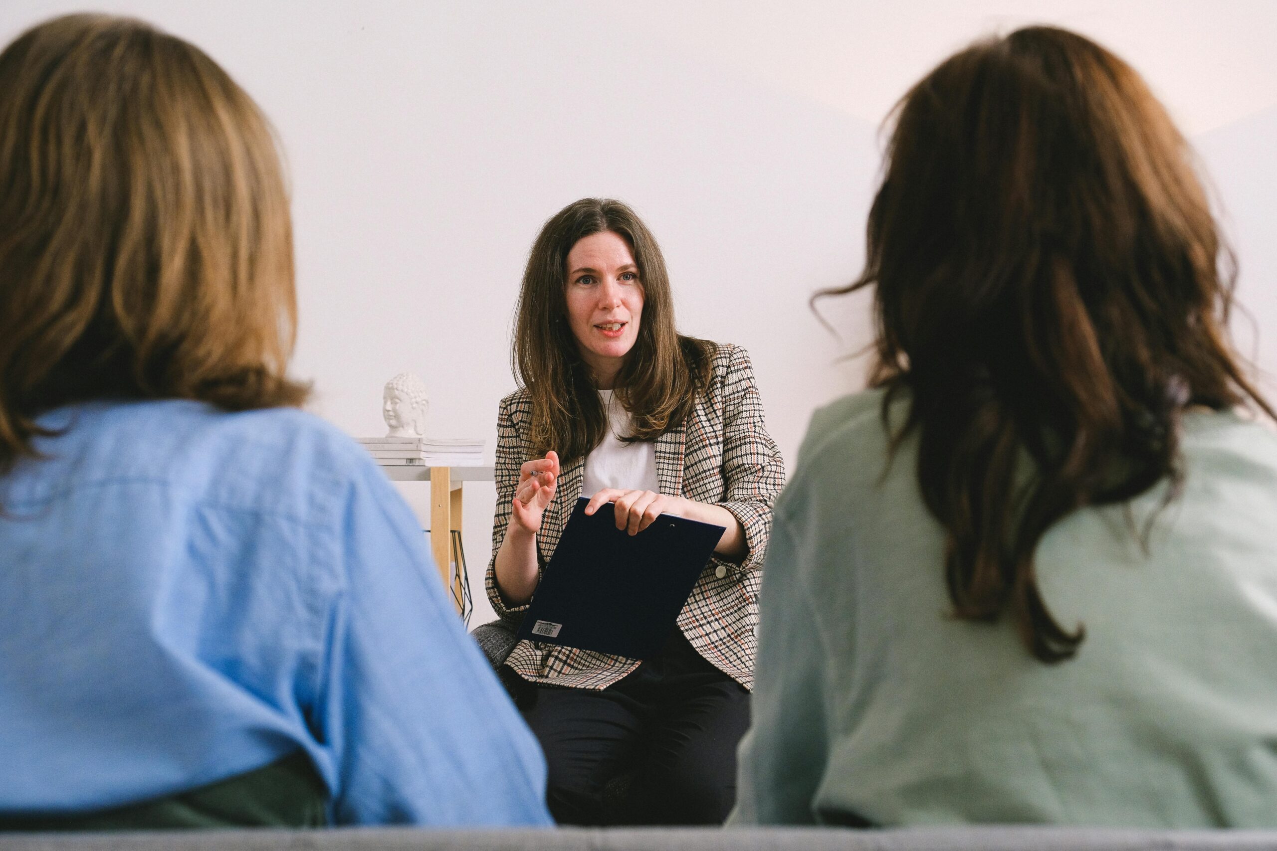 A female psychologist engaging in a therapy session with two individuals, sitting in a cozy office setting