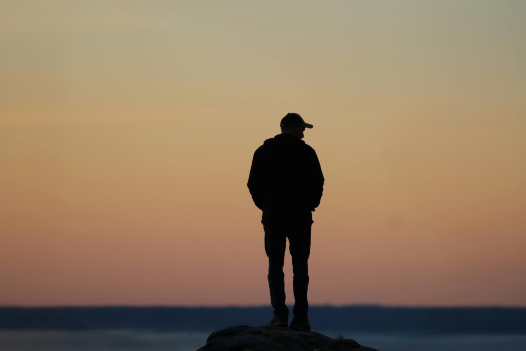 Silhouette of a person standing at sunset, symbolizing introspection and the complexities of attention-seeking behavior.