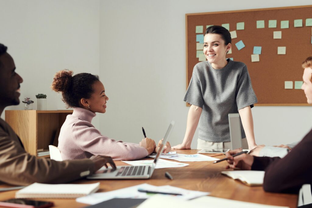 Business team collaborating in a meeting, with one individual standing and appearing to exhibit attention-seeking behavior.