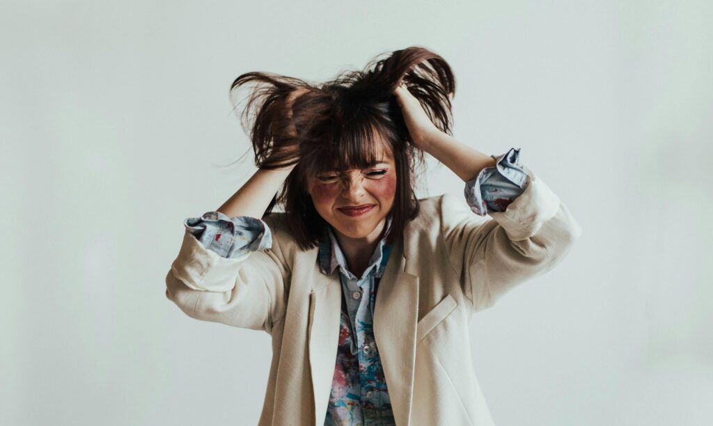 A woman pulls her hair in frustration with exaggerated expression.